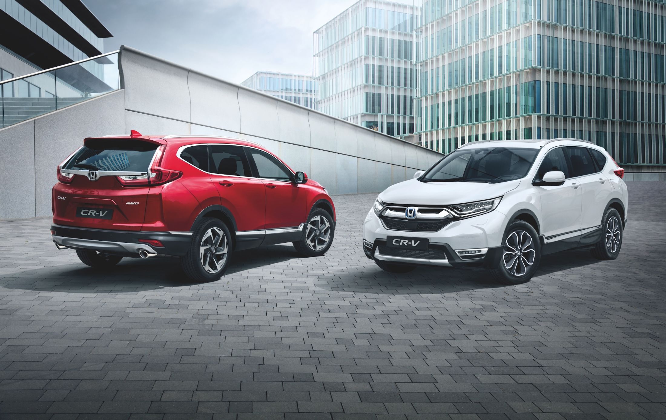 Two parked SUVs, one is red and facing away and the other is white and facing forwards.